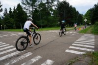 Uczniowie szkoły podstawowej jadą drogą w miasteczku rowerowym po trasie egzaminacyjnego przejazdu.