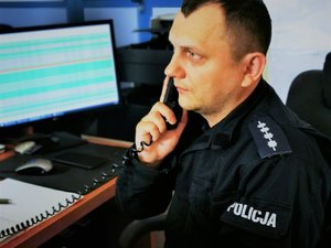 Policjant rozmawiający przez telefon.