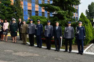 Zdjęcie kolorowe. Widoczni umundurowani policjanci, m.in. nadinsp Roman Rabsztyn, oraz osoby cywilne biorący udział w uroczystości przed budynkiem komendy wojewódzkiej policji