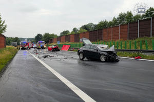 na zdjęciu odcinek drogi, na którym stoją rozbite pojazdy, wozy strażackie i osoby