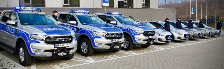 Policjanci stoją przy nowych radiowozach.
