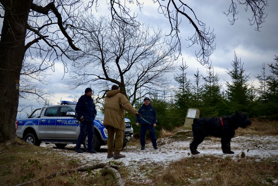 Policjanci rozmawiają z turystą na szlaku górskim.