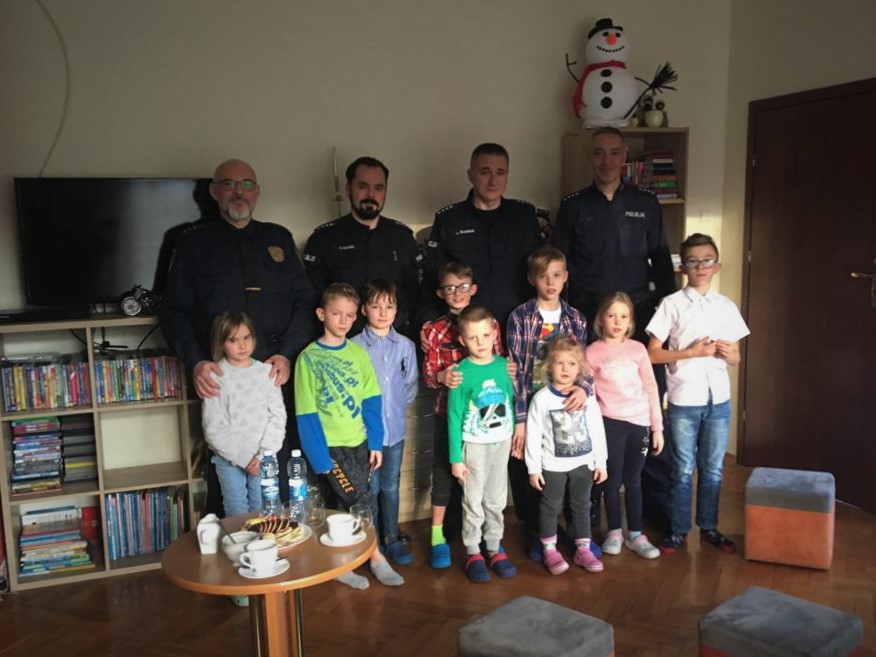 Policjanci, Strażnik Miejski i dzieci z domu dziecka na wspólnym zdjęciu podczas spotkania świątecznego.v