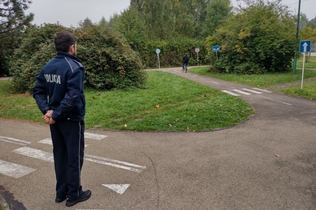 Policjant ruchu drogowego obserwuje ucznia jadącego na rowerze podczas egzaminu.