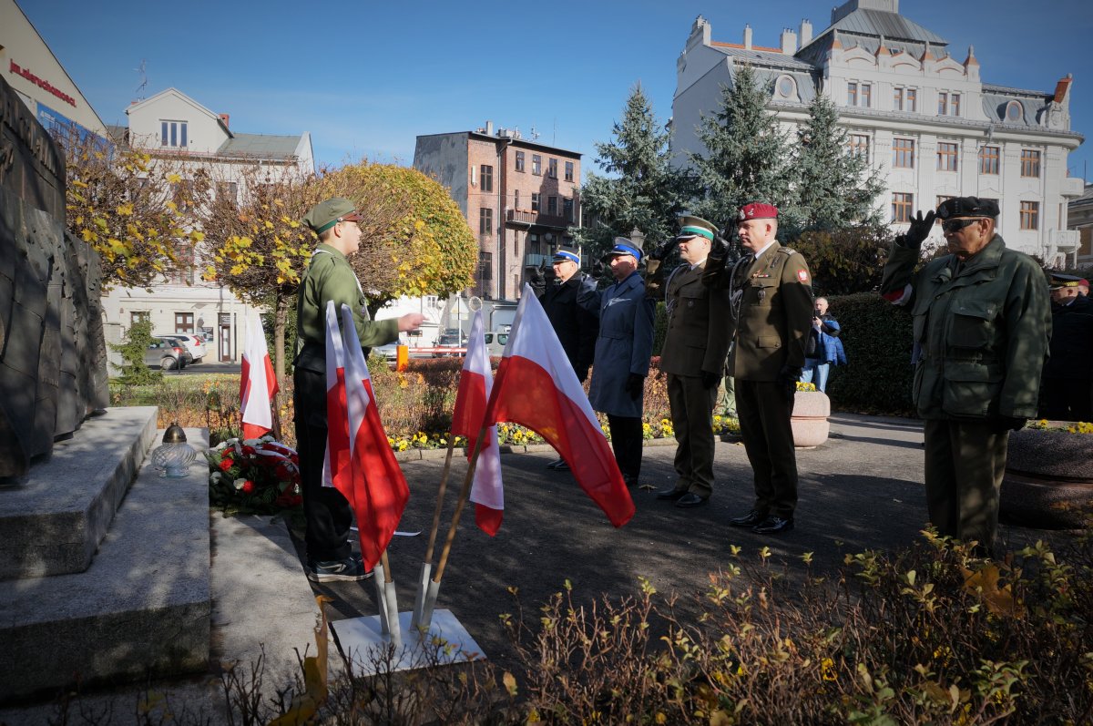 Policjanci i żołnierze oddają honor przed pomnikiem