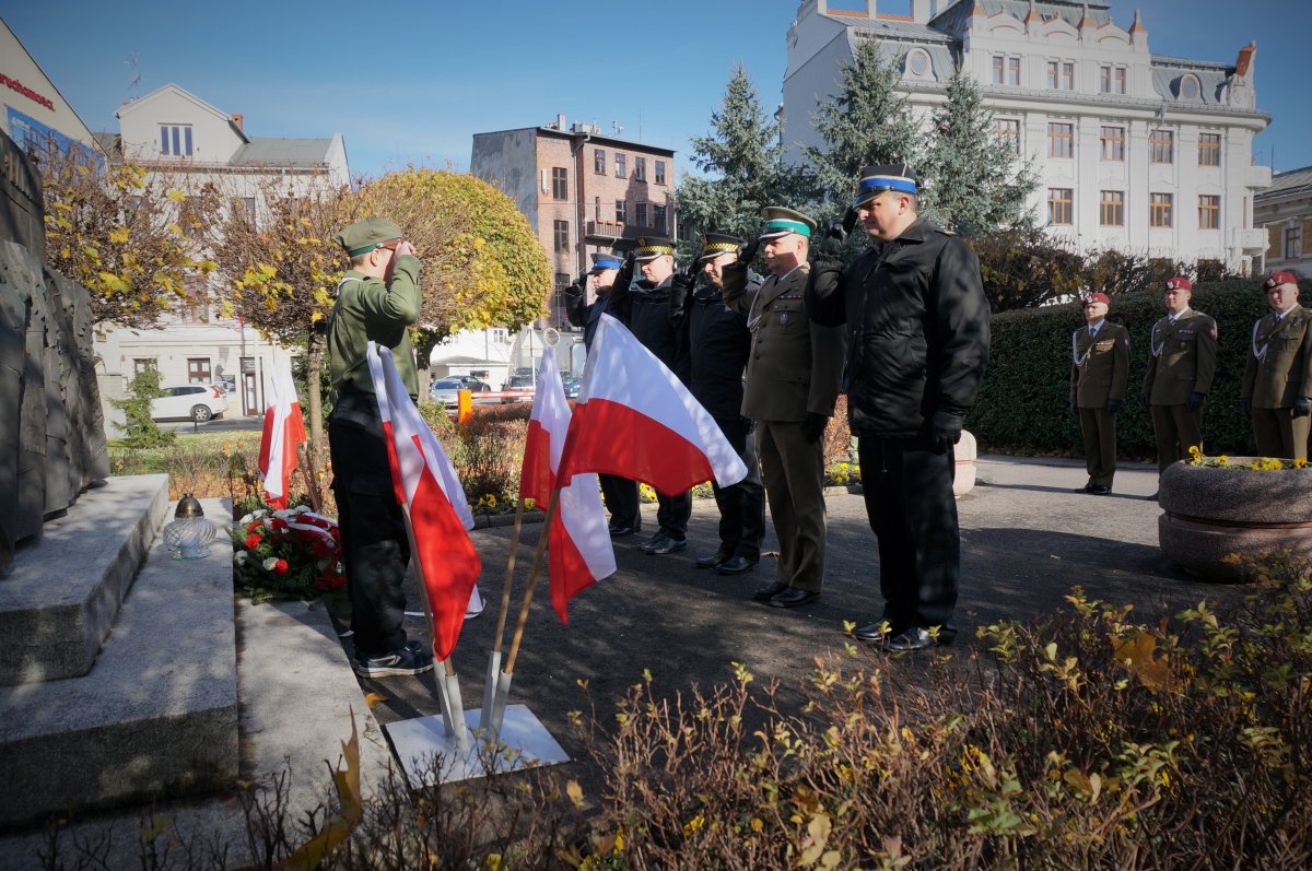 Policjanci i żołnierze oddają honor przed pomnikiem