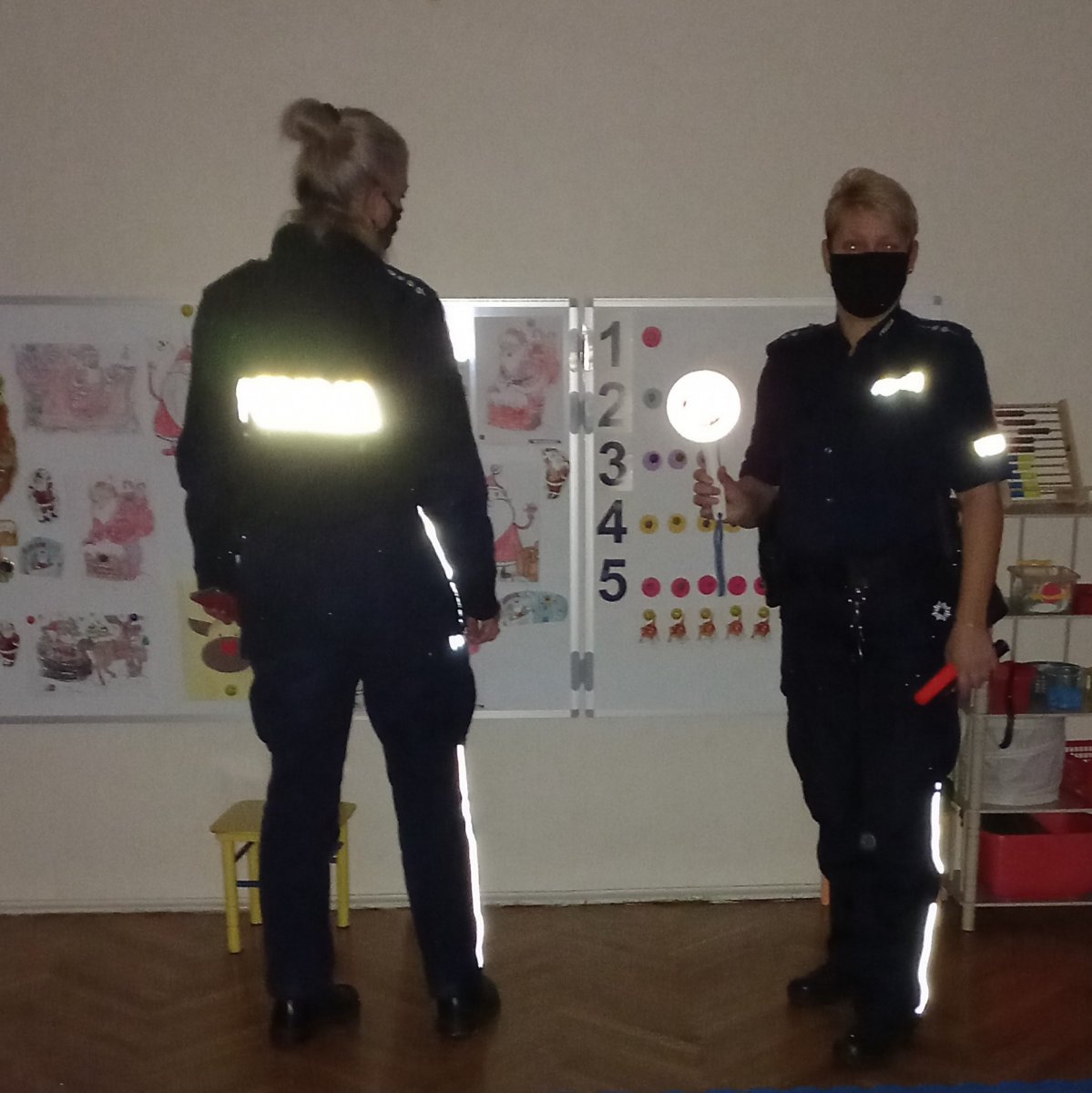 Dwie policjantki w mundurach stoją w sali przedszkola