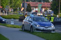 Radiowóz i policjanci z ruchu drogowego w rejonie zamkniętej drogi.