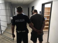 Aresztowany 36-latek doprowadzany przez policjanta z ruchu drogowego.