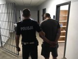 Aresztowany 36-latek doprowadzany przez policjanta z ruchu drogowego.