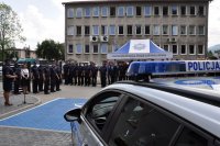 na zdjęciu policjantka podczas przemówienia, policyjny radiowóz oraz policjanci biorący udział w uroczystości