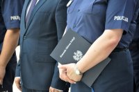 na zdjęciu policjantka trzymająca w dłoniach teczkę z napisem Komenda Główna Policji