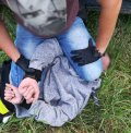 Policjant trzyma obezwładnionego mężczyznę, który posiadał narkotyki.