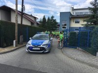 Policyjny radiowóz prowadzi rajd rowerowy.