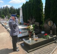 Policjant stoi nad grobem i oddaje honor.