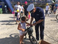 Policjant zakłada dziewczynce lampkę rowerową.