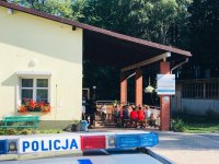 Policyjny radiowóz na tle hufca harcerskiego.