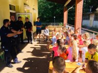 Policjanci prowadzą prelekcję na temat bezpiecznego wypoczynku z zuchami harcerskimi.
