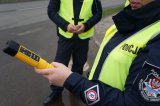 Policjant trzyma w ręku alkomat.