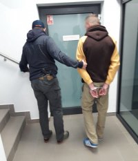 Policjant prowadzi zatrzymanego.
