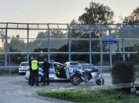Policjanci stoją przy radiowozie i zatrzymanym do kontroli drogowej motocyklu.