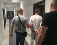 Policjanci prowadzą podejrzanego o zabójstwo.