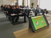Pulpit na sali odpraw, w tle policjanci notują polecenia w notatnikach służbowych.