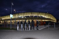 Drużyna policjantów stoi przed stadionem piłkarskim.