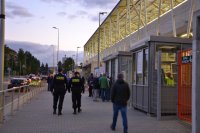 Policjanci patrolują ulicę przy stadionie podczas, gdy kibicie wchodzą na obiekt.