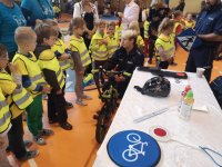 Policjantka pokazuje dzieciom obowiązkowe wyposażenie roweru.
