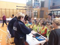 Policjantki przy stoliku uczą dzieci znaków drogowych.