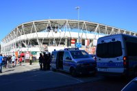Policjanci i strażnicy miejscy stoją przy wejściu na stadion piłkarski.