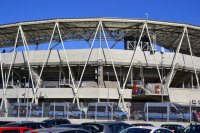 Na parkingu pod stadionem stoją zaparkowane policyjne radiowozy.