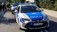 Policyjny radiowóz, w tle uczestnicy rajdu.