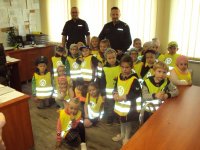 Dzieci z przedszkola i policjanci stoją razem w gabinecie komendanta komisariatu.