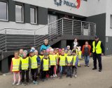 Dzieci w kamizelkach odblaskowych stoją przed wejściem do Komisariatu Policji w Kobiernicach.
