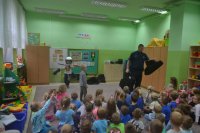 Dzielnicowy prezentuje przedszkolakom wyposażenie policyjne.