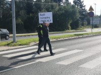 Pieszy przechodzi przez jezdnię z napisem o treści bądź rozsądny zwolnij.