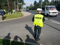 Policjant z drogówki, w tle podjeżdża auto.