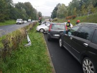 Cztery pojazdy stoją po zderzeniu na jezdni, pomiędzy nimi strażacy.