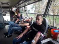 Trzech policjantów w ubraniach cywilnych oddaje krew w specjalistycznym autokarze.