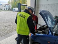 Policjant i diagnosta stoją przy samochodzie z otwartą maską.