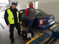 Policjant i diagnosta stoją przy samochodzie.