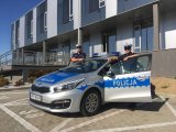 St. sierż. Kamil Foszcz i sierż. Krzysztof Jarzyna stoją przy oznakowanym radiowozie przed budynkiem Komendy Miejskiej Policji w Bielsku-Białej.