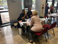 Policjanci siedzą przy stoliku i rozmawiają z kobietą.
