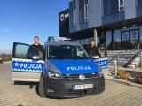 sierż. szt. Piotr Danielczyk i sierż. szt. Bartosz Matuszny stoją przy oznakowanym radiowozie przed budynkiem bielskiej komendy Policji.