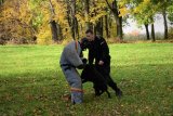 Policjant z psem służbowym ćwiczą obezwładnienie przestępcy, w jego roli policjant w specjalnym ubraniu ochronnym.