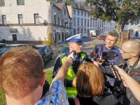 Policjant udziela wywiadu dziennikarzom.