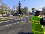 Policjant obserwuje zachowanie pieszego na oznakowanym przejściu.