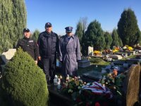 Delegacja policjantów z uczniem klasy mundurowej stoi przy grobie poległego policjanta.